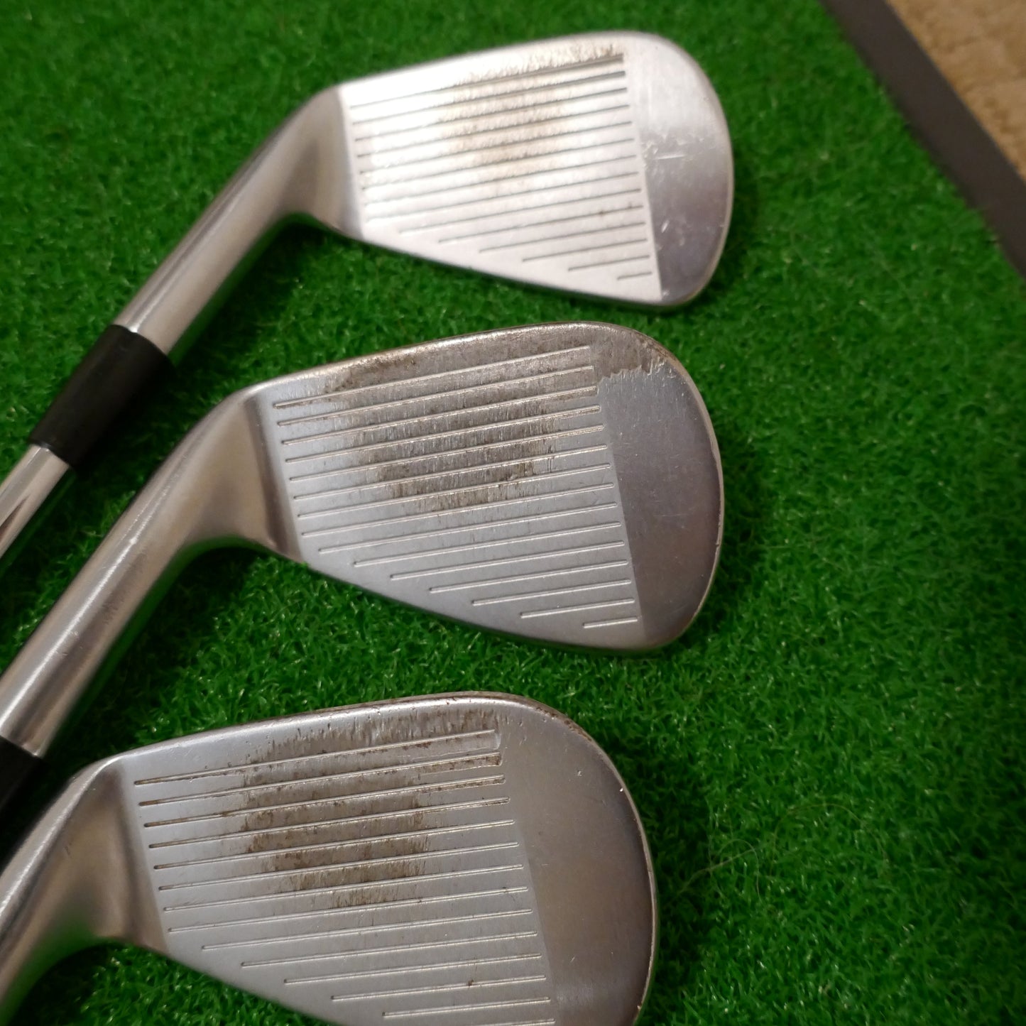 Three golf clubs on a green surface